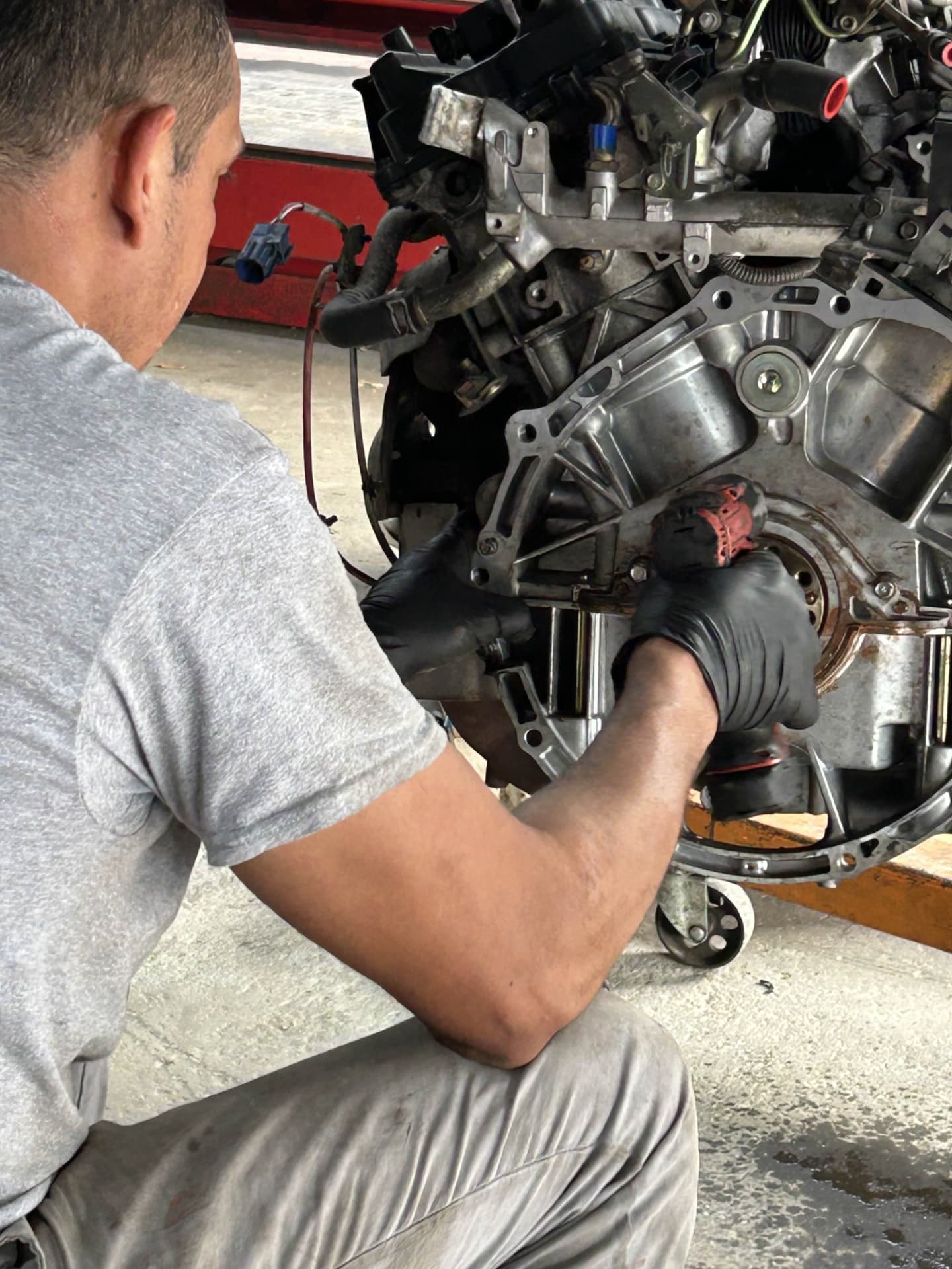 Technician servicing a V6 engine block on a stand during an engine repair at Champion Tires & Brakes