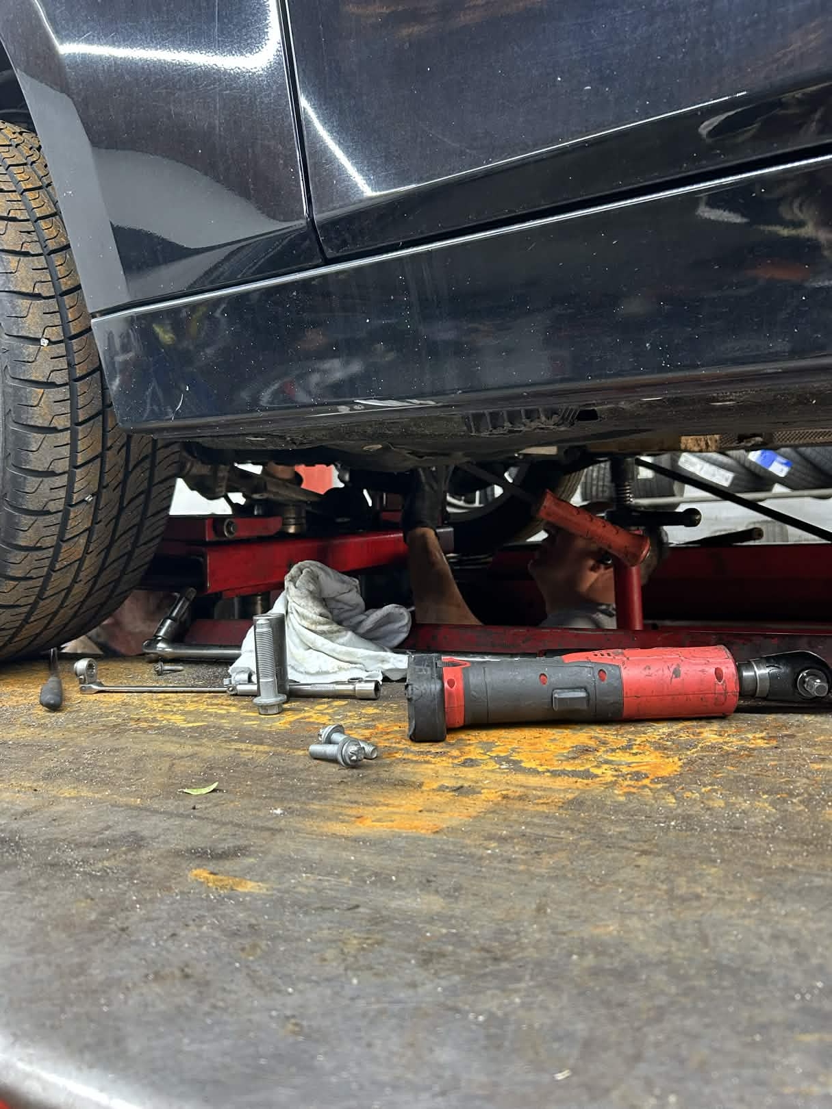 Mechanic working under a car with an air ratchet during a suspension repair