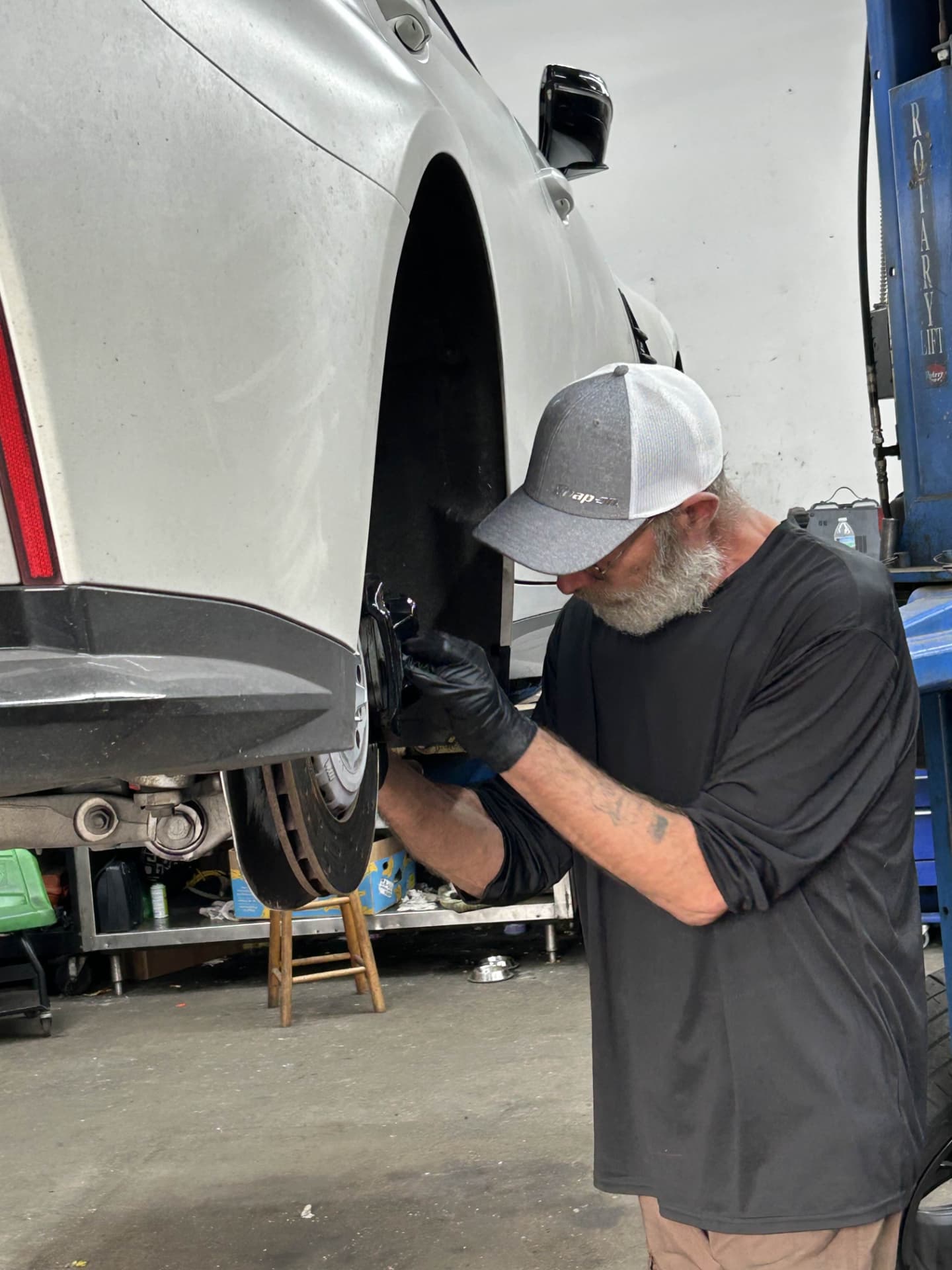 Champion mechanic replacing rear brake pads and rotors on a lifted vehicle