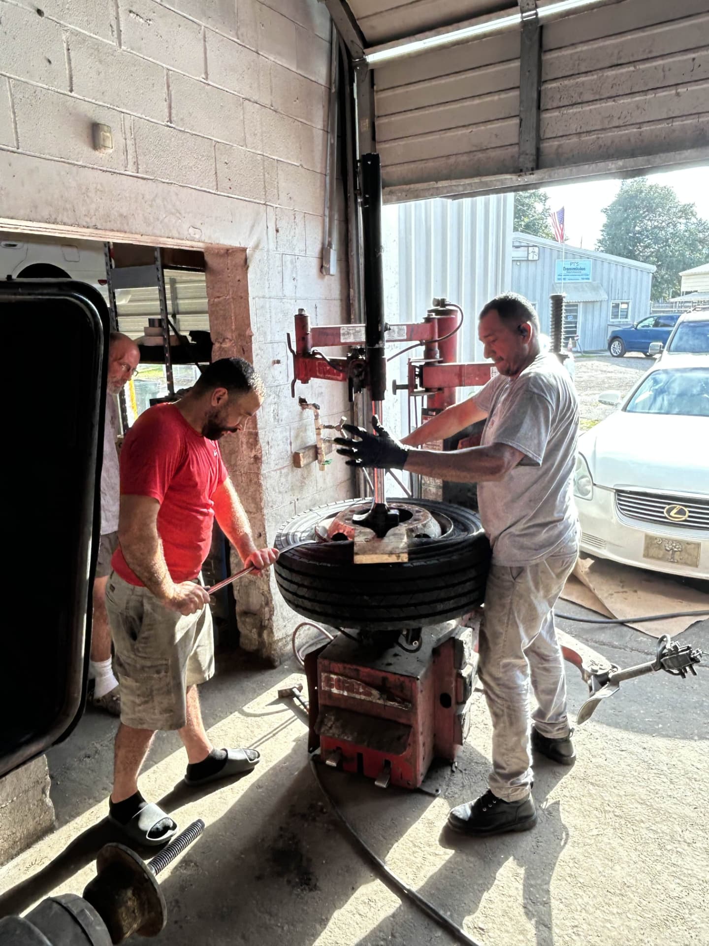 Two Champion Tires & Brakes technicians breaking down a truck tire on the tire machine